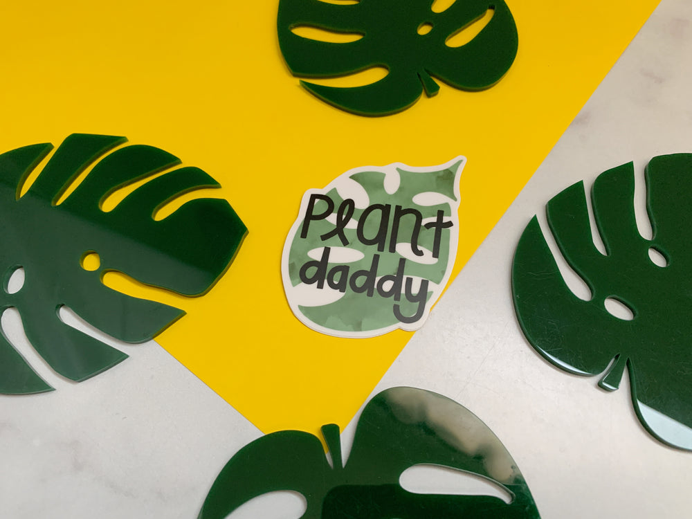 Green leaf-shaped cutouts with 'Plant daddy' sticker on a yellow and white background