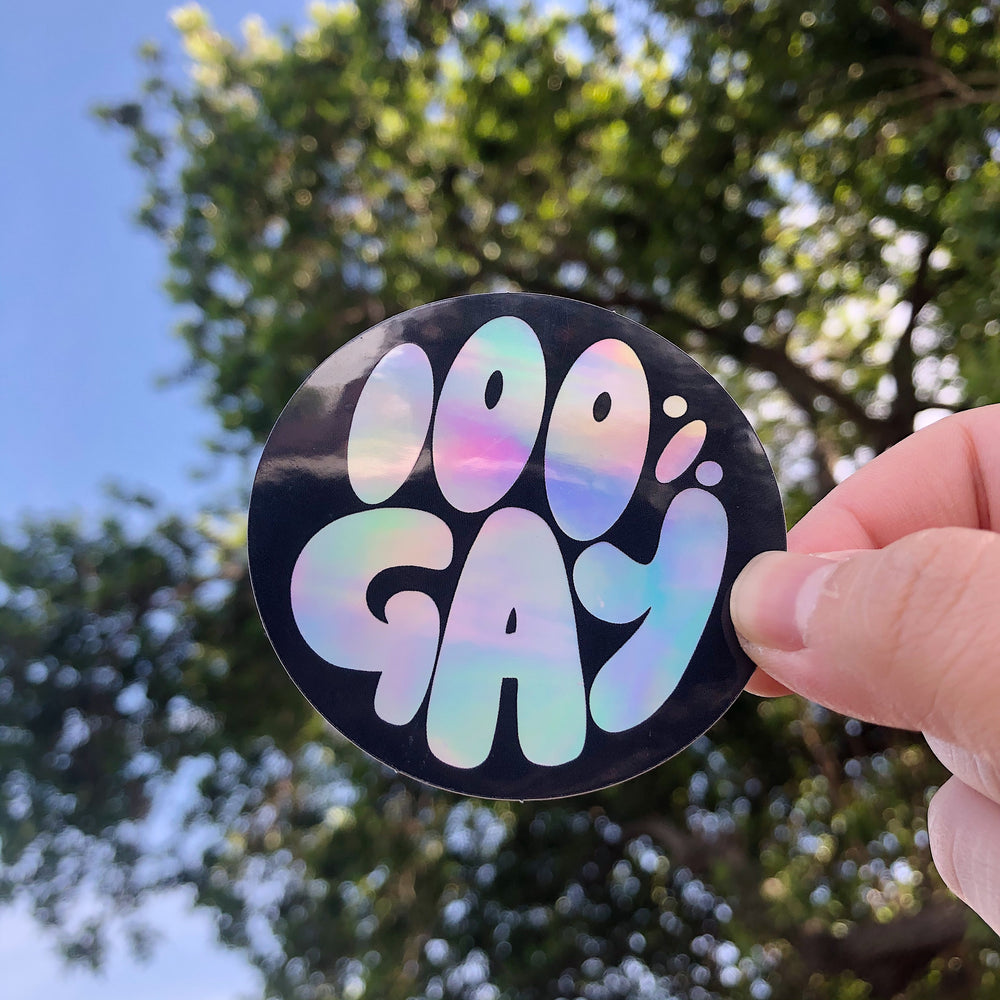 Decorative sticker with text '100% Gay' with trees and sky background
